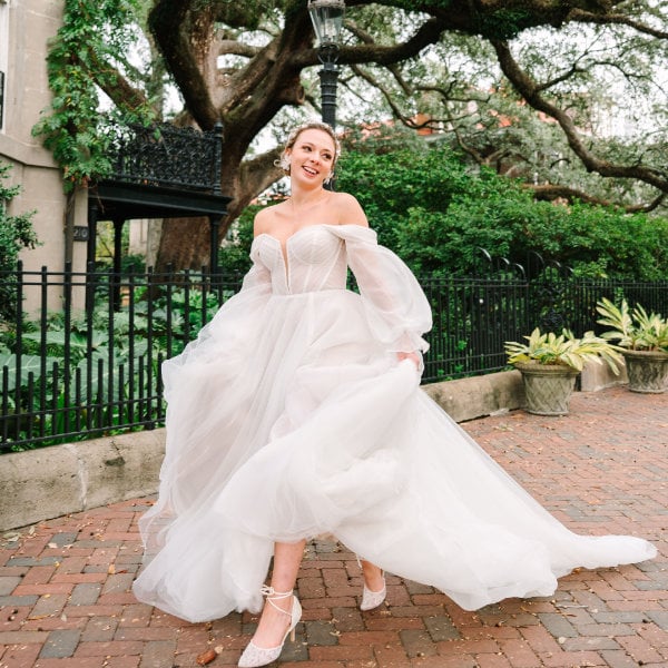 a bride running in her wedding dress down a sidewalk