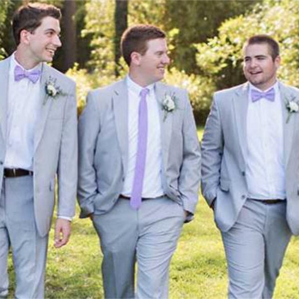 a groom and his groomsmen walk in a field whild laughing