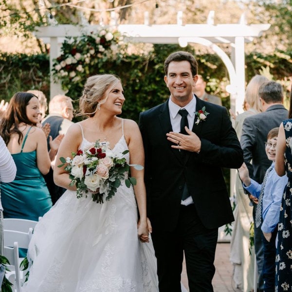 a bride and groom walk down the aisle holding hands